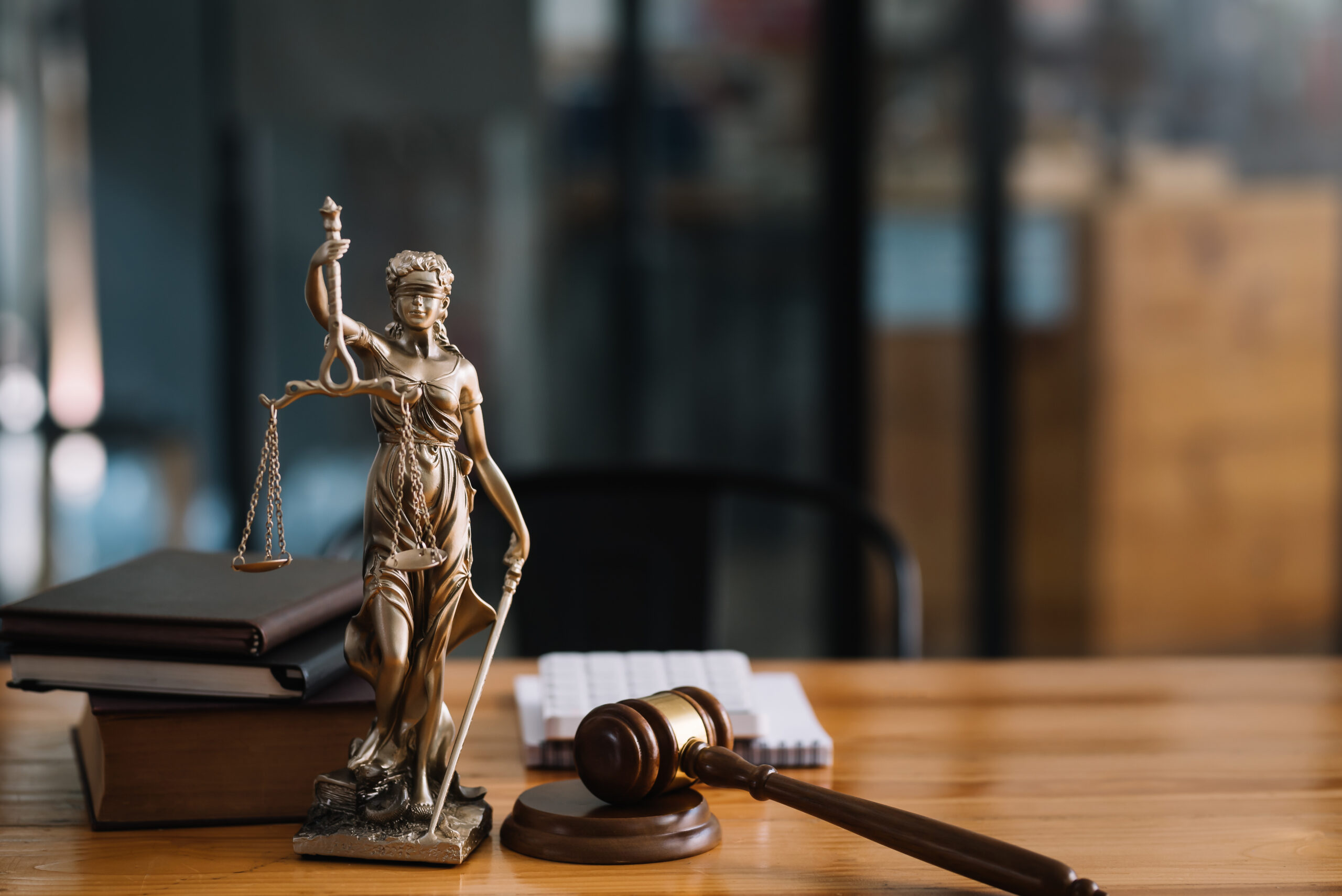 Statue von Justicia mit dem Richterhammer auf Tisch